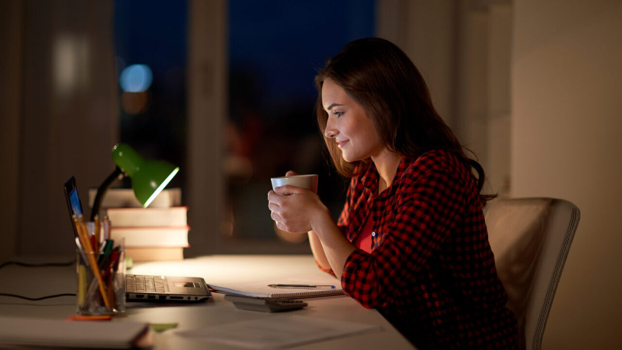 woman with laptop drinking coffee at night.