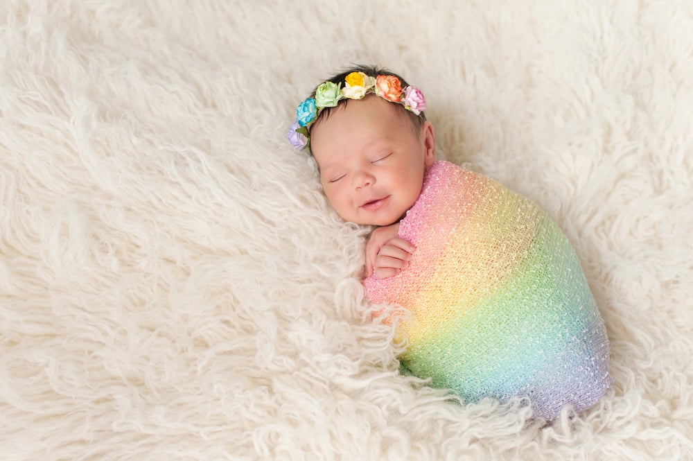 baby wrapped in a rainbow blanket asleep