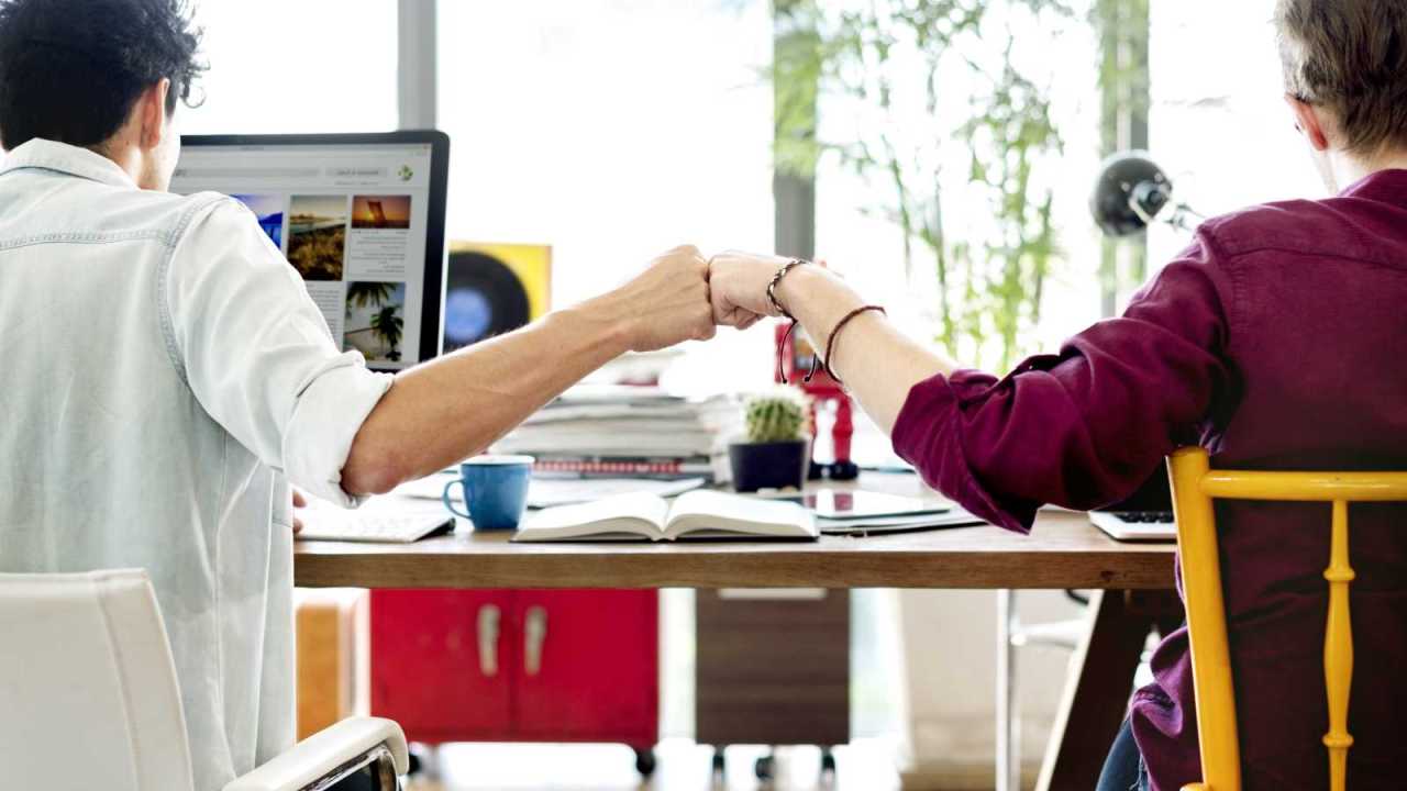 Friends at work give fist bump.