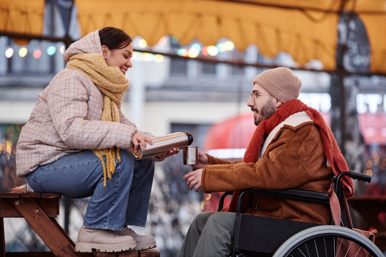 Young couple sharing hot drink while enjoying date in winter outdoors.