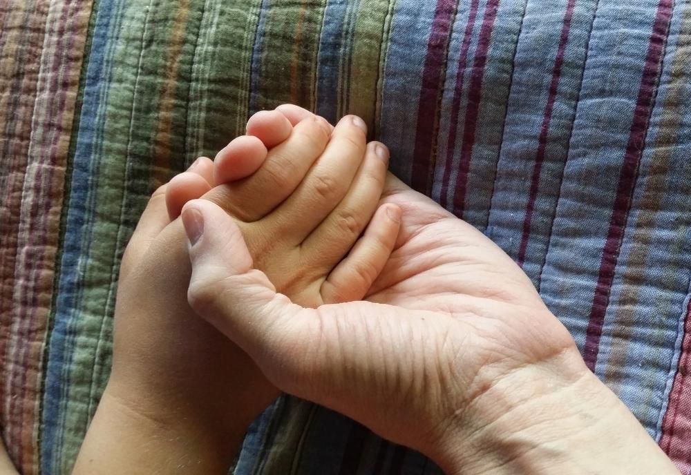 A mom and a child's hands are clasped together