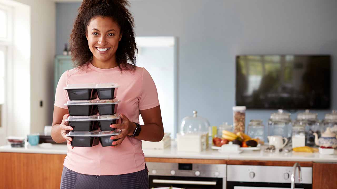 Woman holding a few prepped meal containers.