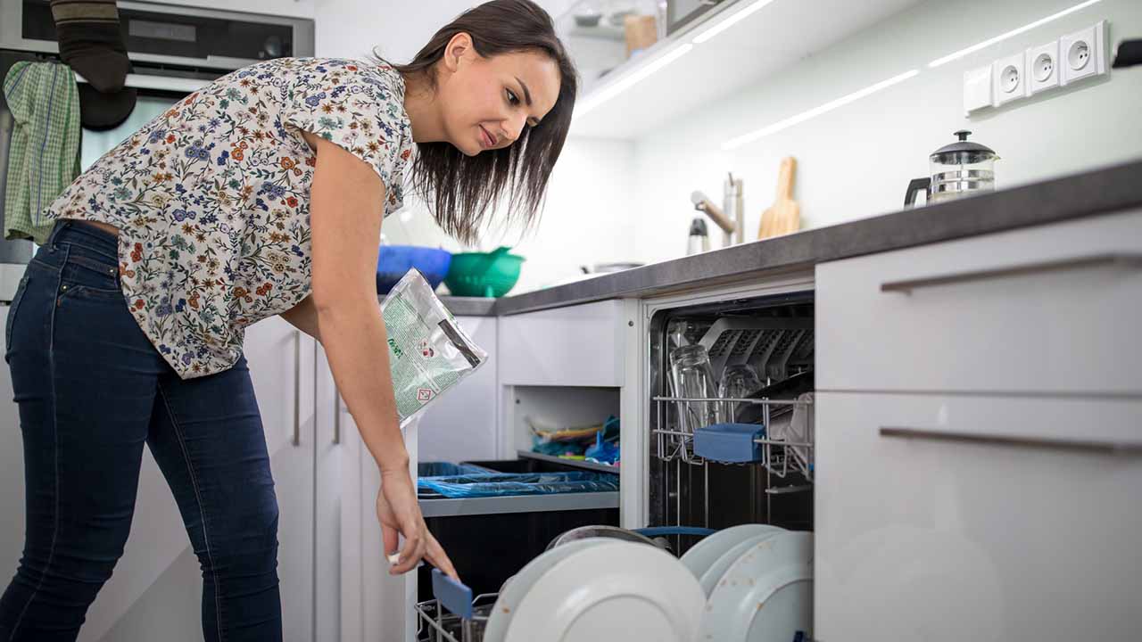 person doing daily cleaning in kitchen and running dishwasher.