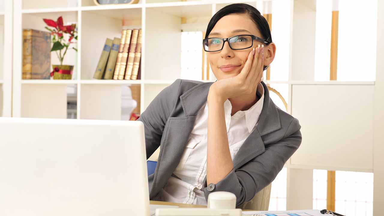 woman at desk daydreaming.