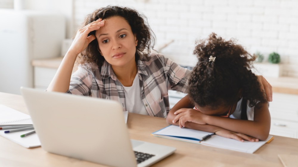 Mom sitting next to child in front of computer. child looks tired and mom looks frustrated