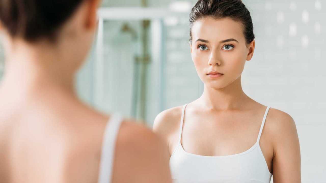 serious woman looking at herself in the mirror.