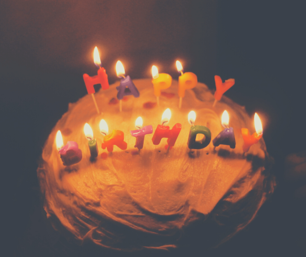 Birthday cake has candles spelling out happy birthday lit on top